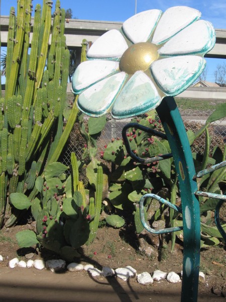Flower sculpture and cacti beside freeway.