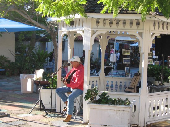 Man plays guitar in Spanish Village gazebo.