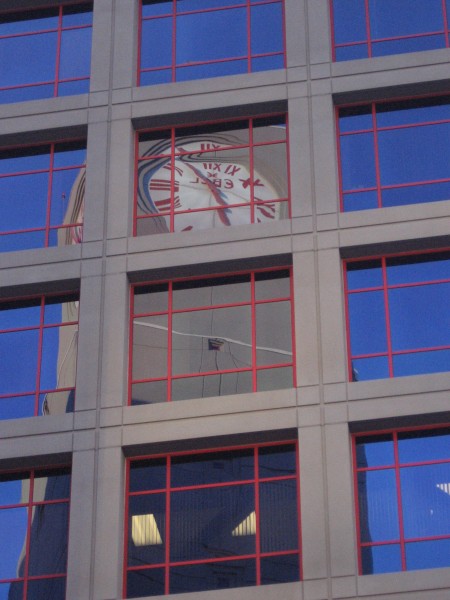 Clock tower at 12th and Imperial trolley station reflected in windows.