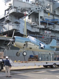 Crane begins to lift F4F Wildcat onto USS Midway.