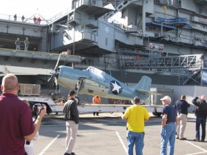 Historic airplane transported by truck to USS Midway.
