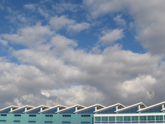 Roof of Broadway Pier Port Pavilion and clouds in blue sky.