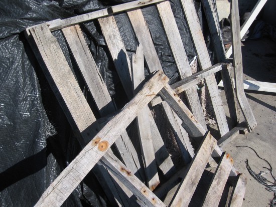 Broken pallets lean against mound of nets covered in plastic.