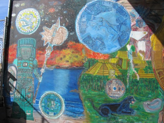 Aztec mural painted near chain link fence.