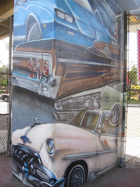 Classic cars depicted on a concrete pillar.