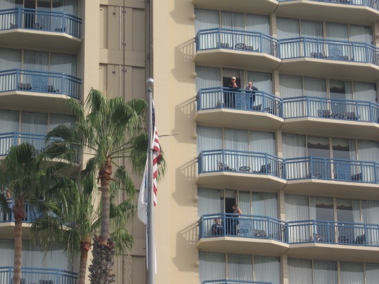 People watch parade from hotel balconies across the street.