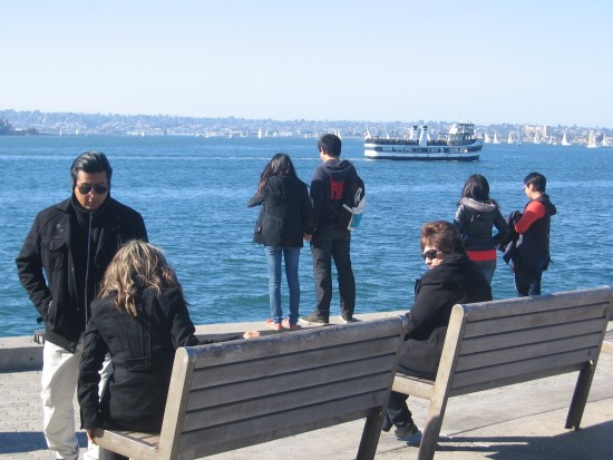 People gaze at San Diego Bay from benches by The Fish Market.