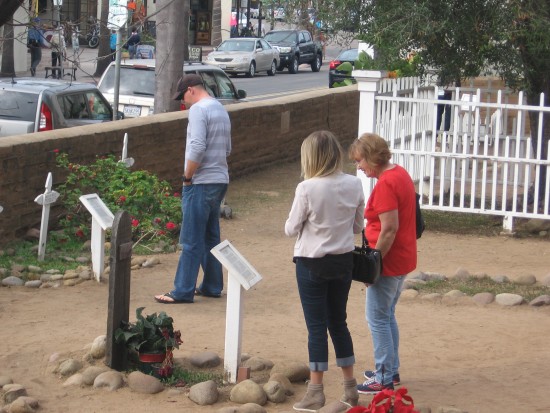 People read plaques and headstones in Old Town cemetery.