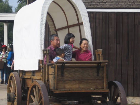 Tourists pose for a picture in an old covered wagon in Old Town.
