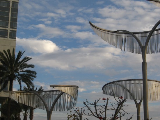 Clouds above metal trees in front of Hilton hotel.