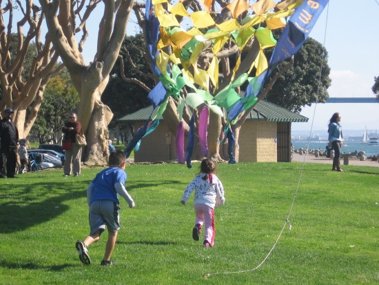 Children play beneath colorful kite near Seaport Village.