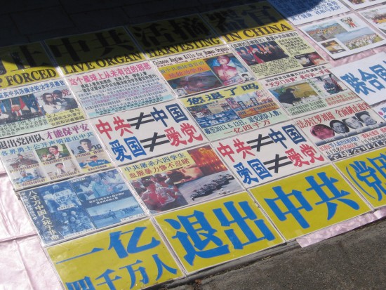Falun Gong poster on sidewalk near Unconditional Surrender statue.