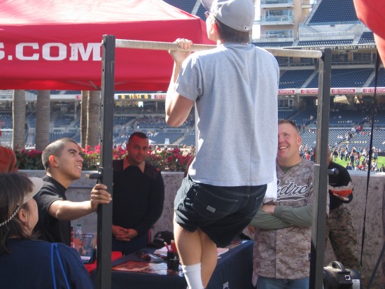 Padres fan does pull-ups at Marines booth at Fanfest.