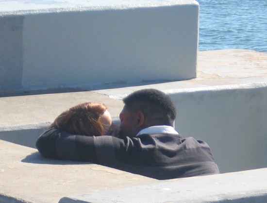 Lovers have an intimate moment by the water.