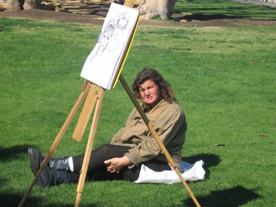 Resting on the grass, waiting to sketch a tourist portrait.