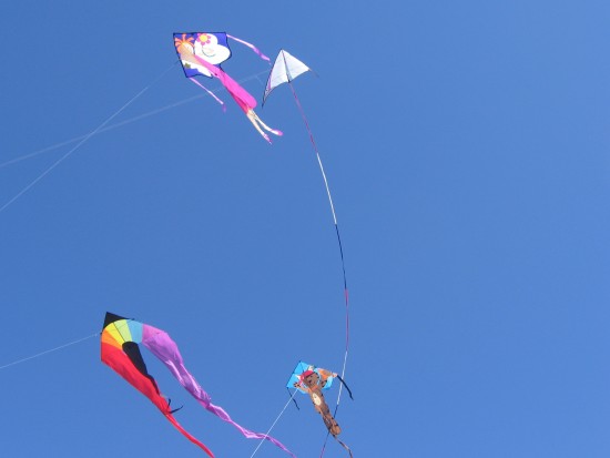 Four colorful kites in a clear blue sky.