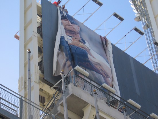 Two workers put up large Padres banner at Petco Park.