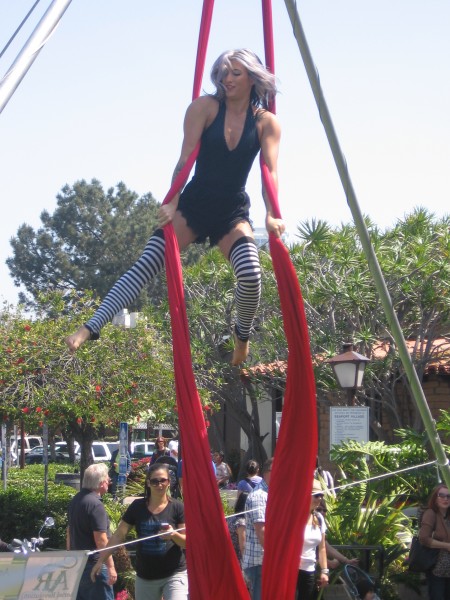 Aerial silks dancer performs near Seaport Village carousel.