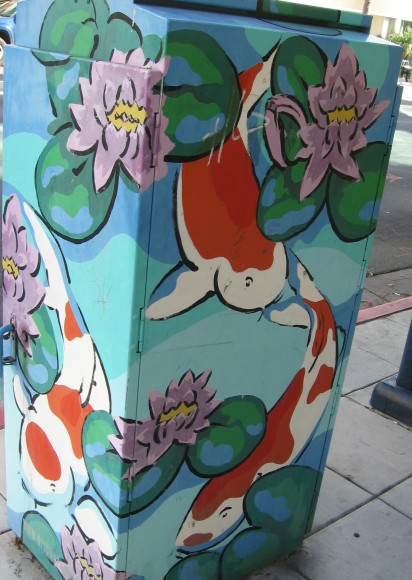 Koi and pond flowers adorn a colorful utility box.