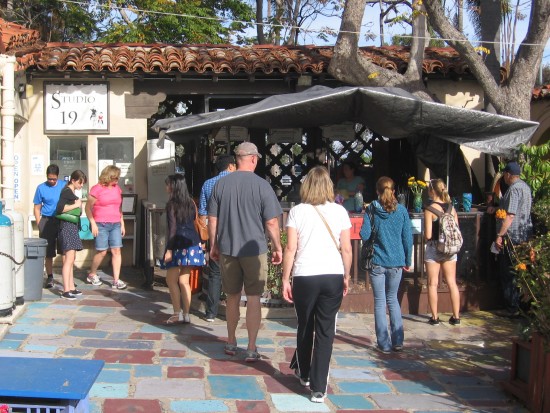 People converge to see glassblowing in progress.