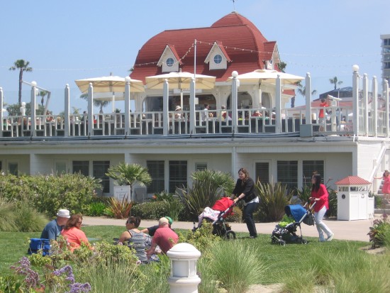 Pushing strollers past some outdoor dining.