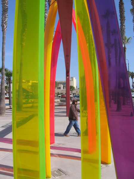 Colorful surfboard arches frame a pier visitor.