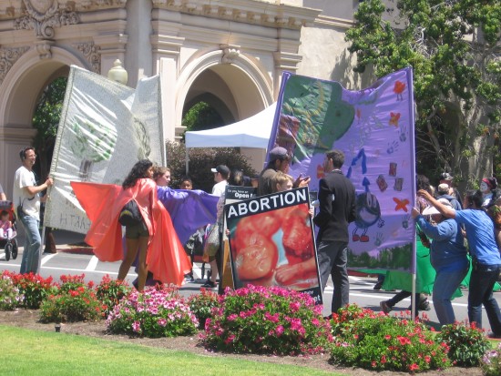 Earth Day activists conceal anti-abortion sign with banners.