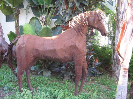 Handsome metal horse looks out toward street.