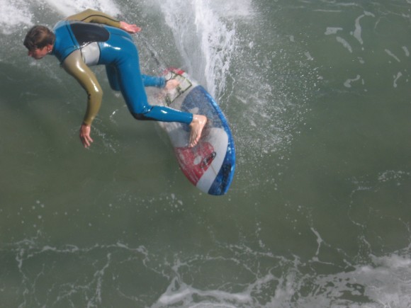 Surfer rides a wave just below the Imperial Beach pier.
