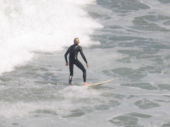 Guy on surfboard just coasting along the foamy ocean surface.