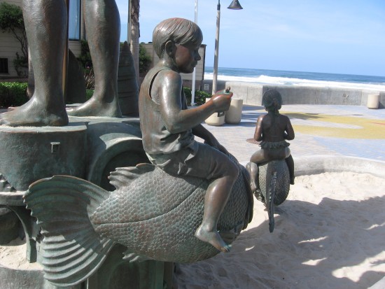 Child rides a fish near the beach.