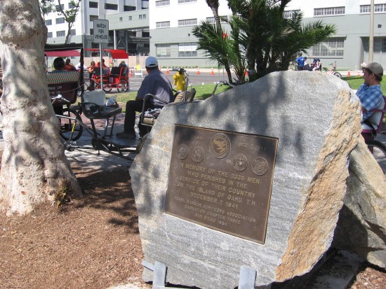 Pedicab drivers wait near Pearl Harbor plaque.