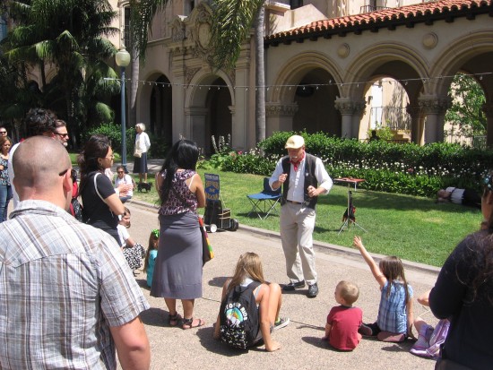 Sleeveless magician performs card trick for rapt audience.