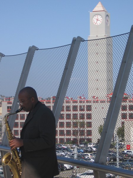 Clock tower above musician on Harbor Drive bridge.