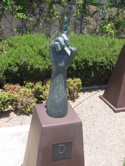Bronze hand signs the letter D.