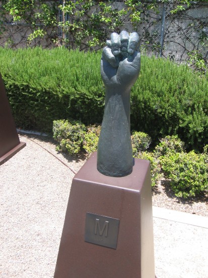 Bronze hand signs the letter M.