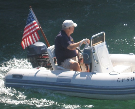Small boat cruises San Diego Bay with flag.