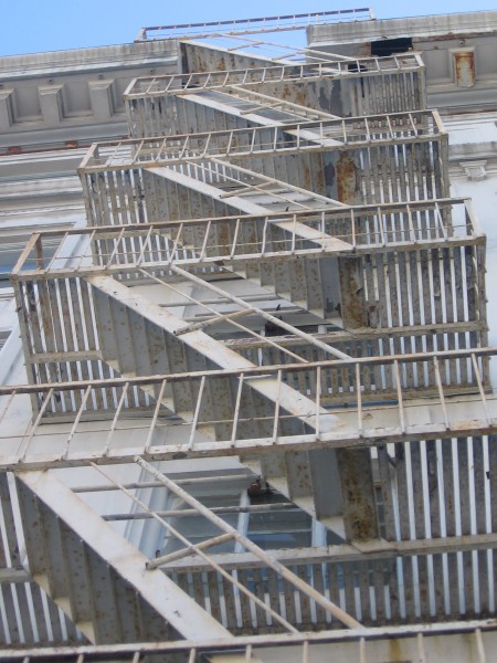 Looking up a rusty old fire escape.