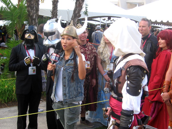 News reporter talks with very elegantly dressed Star Wars characters.