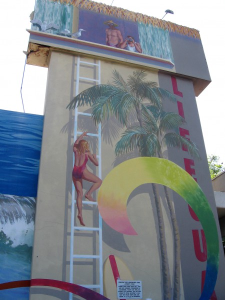 Mural shows lifeguard climbing a tower among palms.