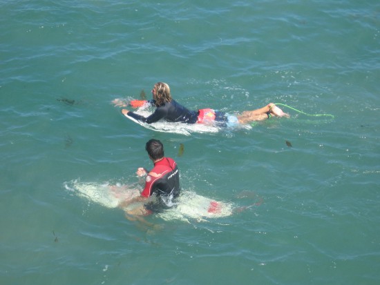 Surfers below Crystal Pier floating and waiting on their surfboards.