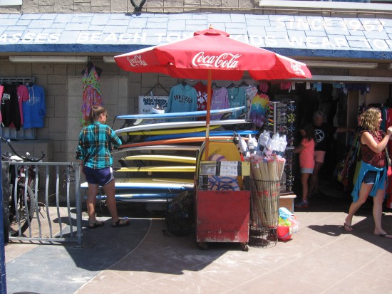 Lady looks through a high stack of surfboards.