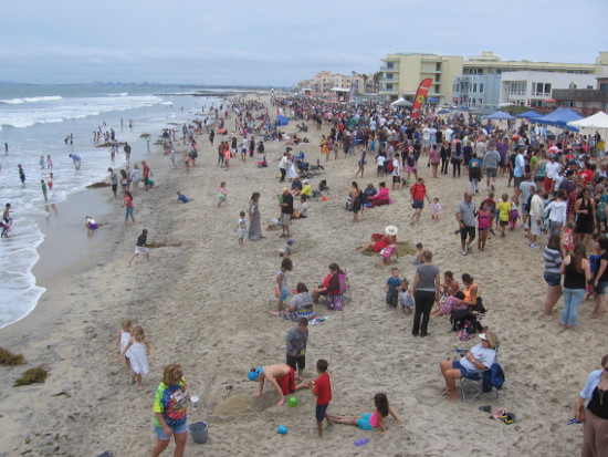 Crowd watches master sand sculptors creating fantastic works of art.
