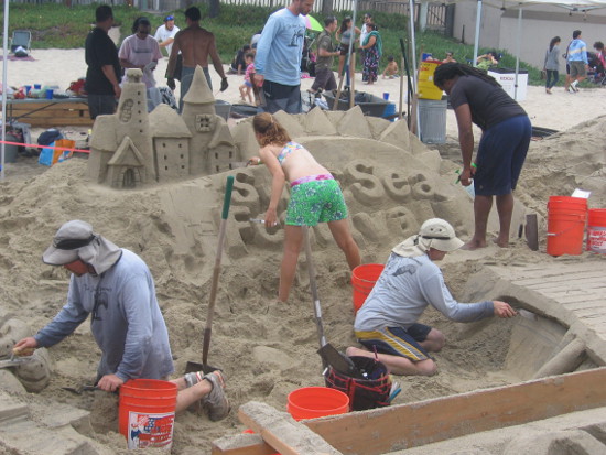 Huge, complex sand sculpture with many team members working.