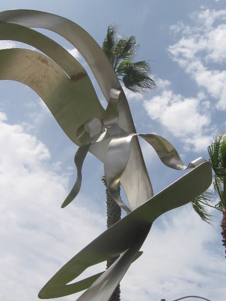 Shiny metal sculpture of abstract surfer on Palm Avenue.