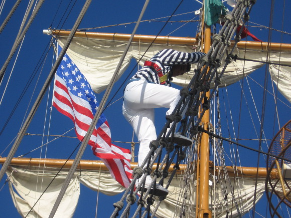 A sailor descends as American flag flies from the visiting vessel.
