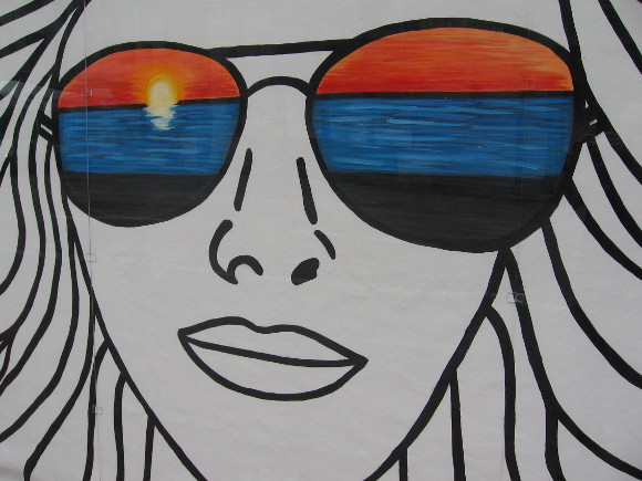 California girl in cool sunglasses watches a sunset.