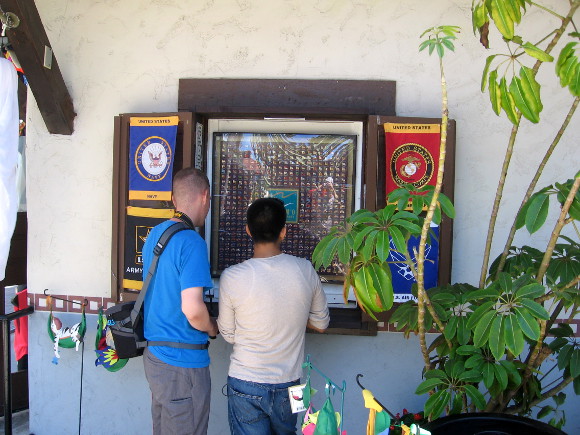Two young men look in window at a huge collection of flag pins.