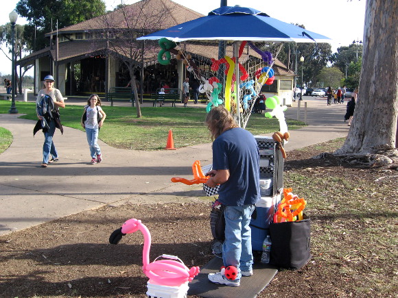 Lady twists balloon creations near the historic Balboa Park carousel.