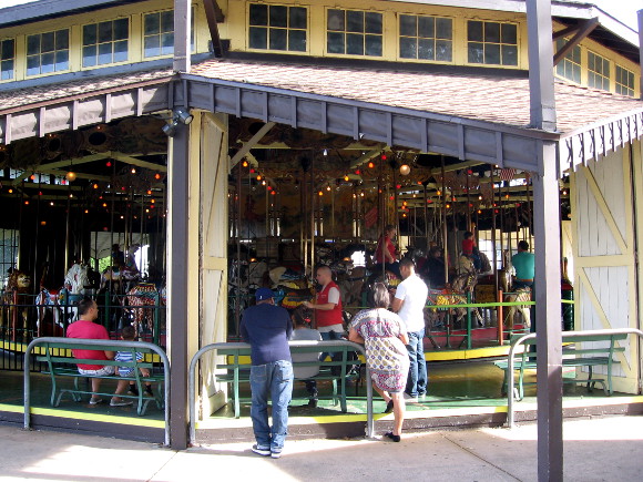 People gaze at the 1910 Herschell-Spillman carousel on a summer day.